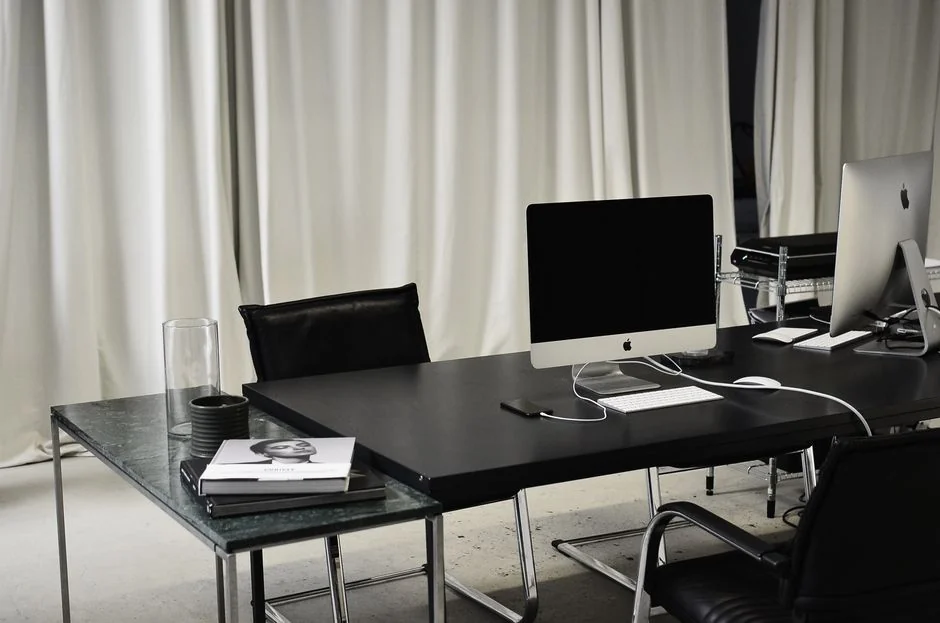 Un espace de travail moderne avec deux écrans d’ordinateur affichant des projets de design web, mettant en avant la technologie et la productivité.